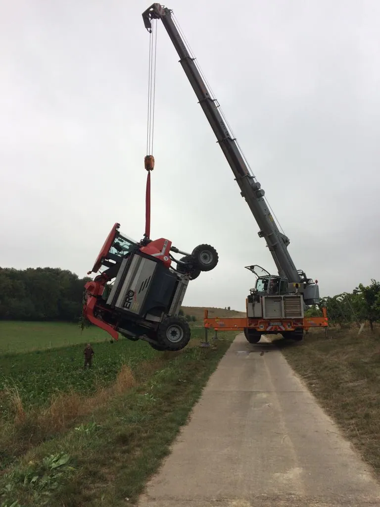 Autokran hebt ein Fahrzeug über einen Feldweg