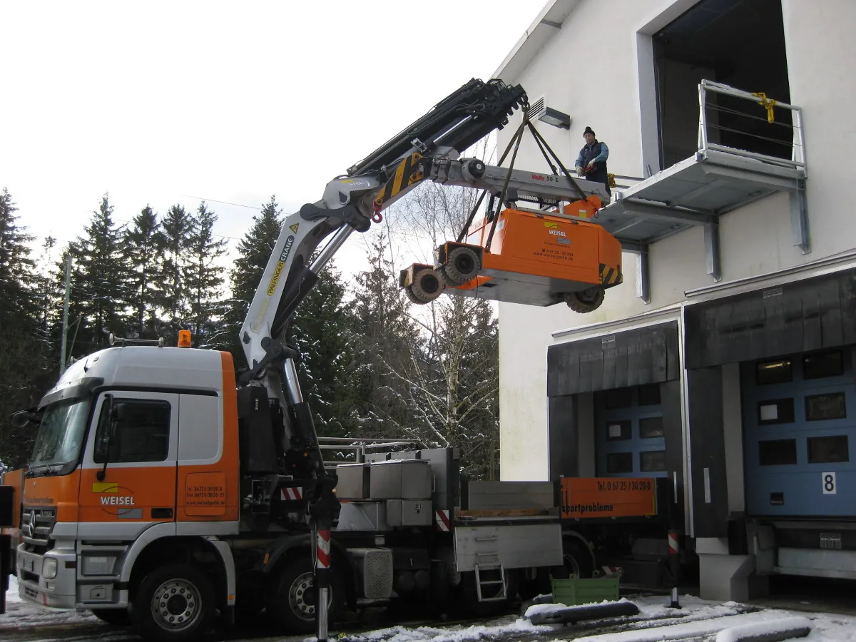 Ladekran-LKW der Weisel GmbH beim Entladen an einem Gebäude