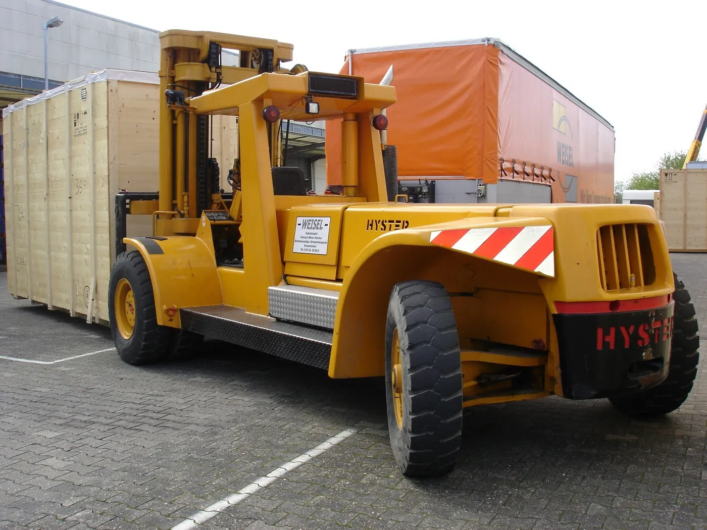 Schwerlaststapler verlädt eine große Transportkiste am Lager