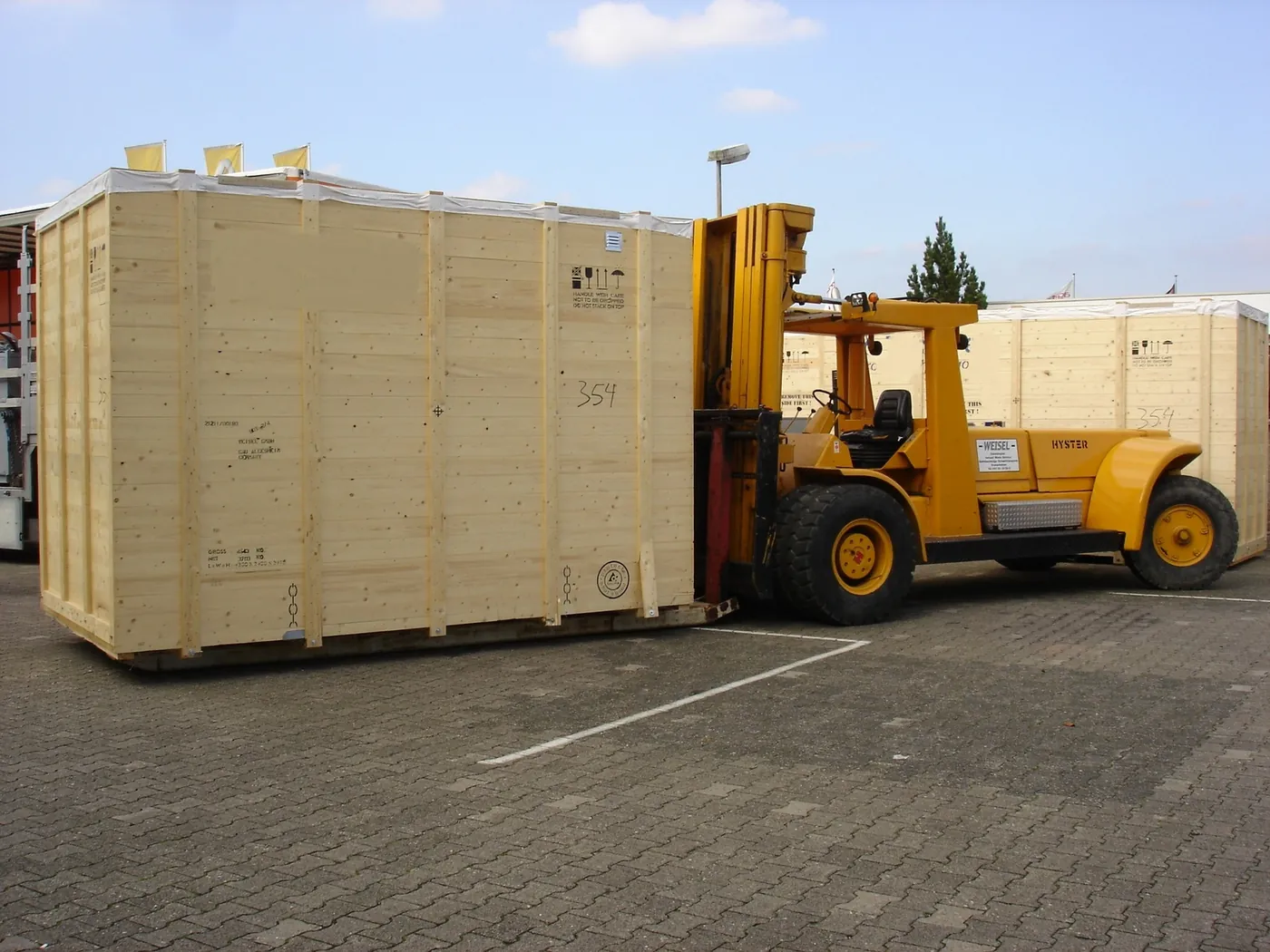 Schwerlaststapler verlädt eine große Transportkiste am Lager